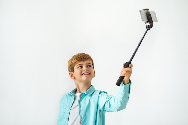 El niño feliz tomando un selfie sobre el fondo blanco.