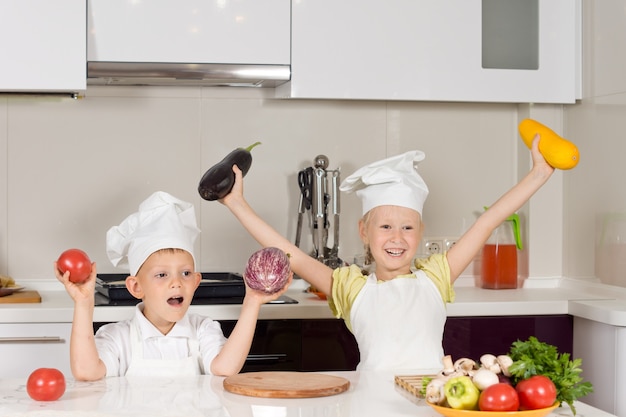 Foto niño feliz en traje de chef con verduras frescas en la cocina