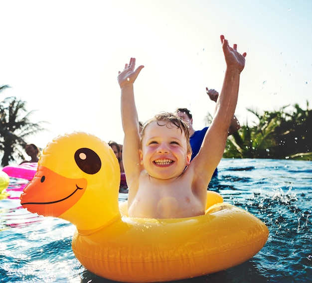 Niño feliz y un tubo de pato amarillo en la piscina