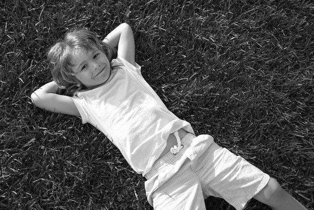 Niño feliz tumbado en el fondo de hierba niño lindo niño niño disfrutando en el campo y soñando unidad con n