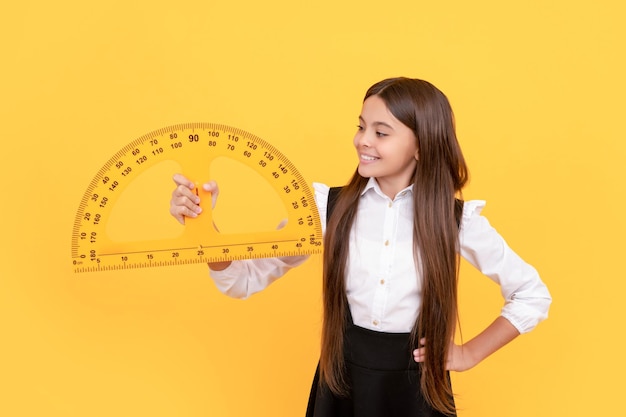 Niño feliz en uniforme escolar sostenga transportador de matemáticas para medir la lógica