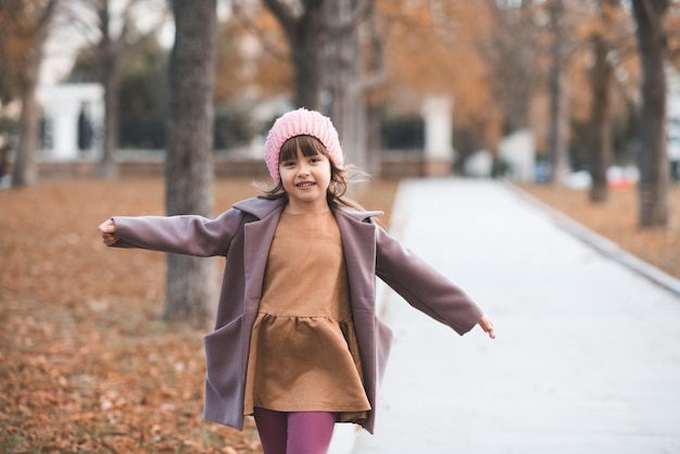 Niño feliz use chaqueta y sombrero en el parque con hojas caídas sobre el fondo de la naturaleza Temporada de otoño