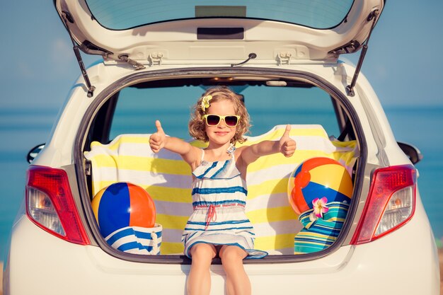 Niño feliz viajando en coche Niño divirtiéndose en la playa Concepto de vacaciones de verano