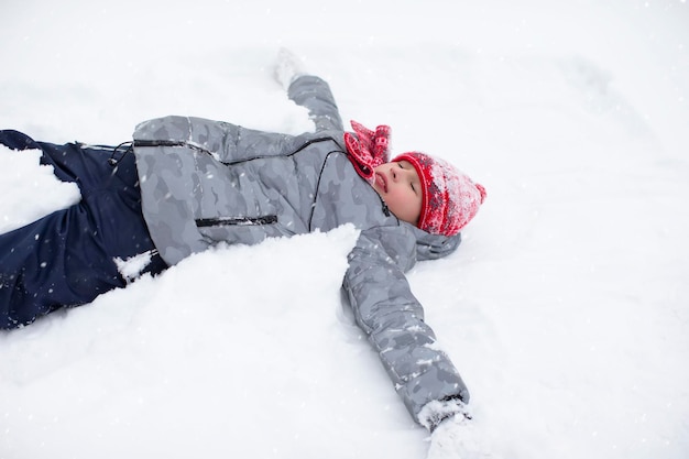 Un niño feliz yace en la nieve y disfruta del clima.