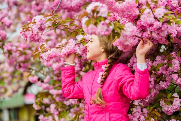 Niño en flores rosas de fondo de árbol de sakura Niño disfrutando de la flor de cerezo rosa Floración tierna El rosa es el color más femenino Brillante y vibrante El rosa es mi favorito La niña disfruta de la primavera