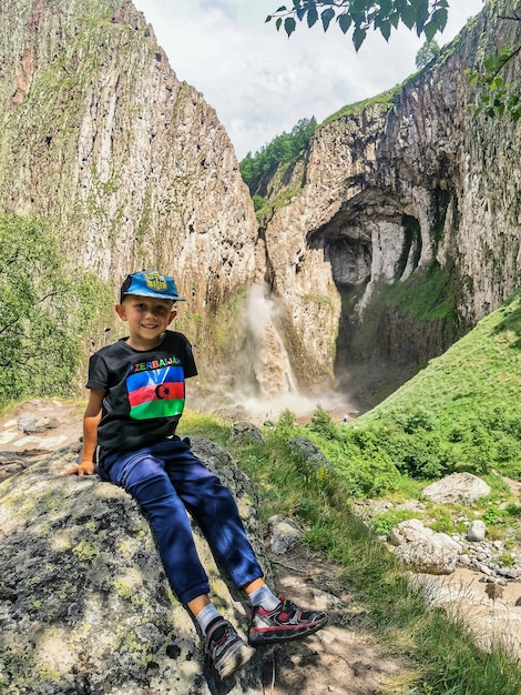 Un niño en el fondo de la cascada KarakayaSu en el territorio de KabardinoBalkaria