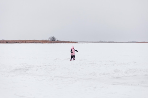 Niño en el fondo del paisaje de invierno niña en traje de brazo y sombrero con pompón se encuentra en snowco ...