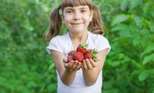 Un niño con fresas en las manos.