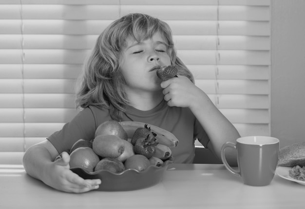 Niño con frutas de verano de fresa niño pequeño que tiene un desayuno saludable nutrición y desarrollo para niños