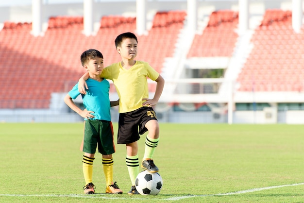 Niño y fútbol en el campo de césped de fútbol