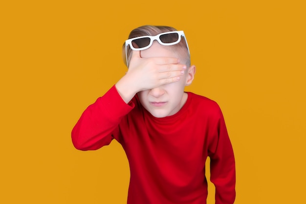 Un niño con gafas 3D para niños se cubrió los ojos con la mano.