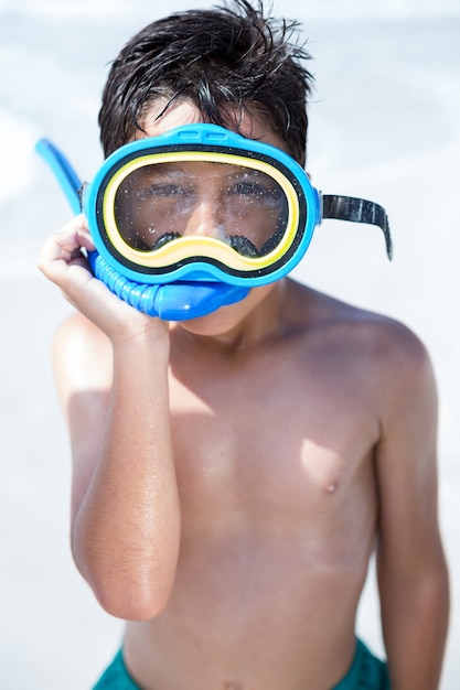 Niño con gafas de buceo de pie en la playa