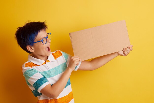 Un niño con gafas de fondo amarillo con diferentes emociones sostiene una pancarta de cartón