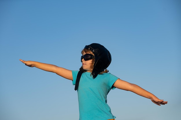 Niño con gafas de piloto y casco soñando y juega con un avión de juguete en el cielo sueña con viajar develo