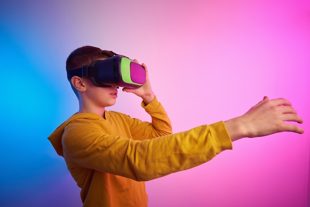 Niño con gafas de realidad virtual en el fondo de colores