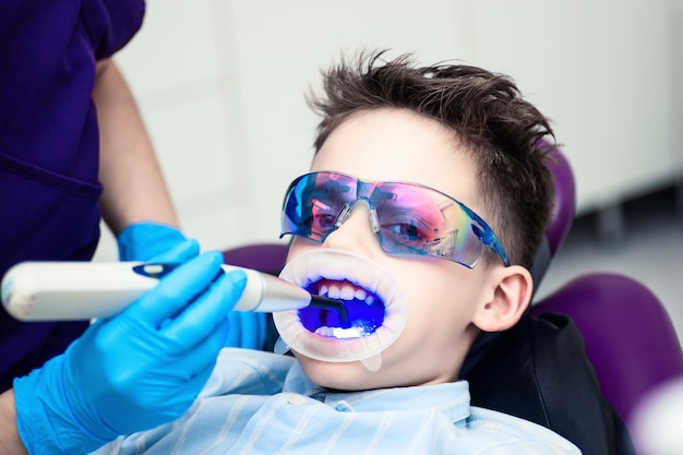 Un niño con gafas en la silla dental.