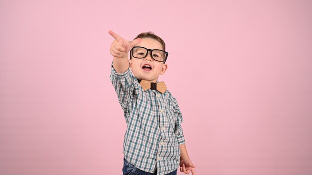 Niño con gafas, sobre un fondo rosa. Foto de alta calidad