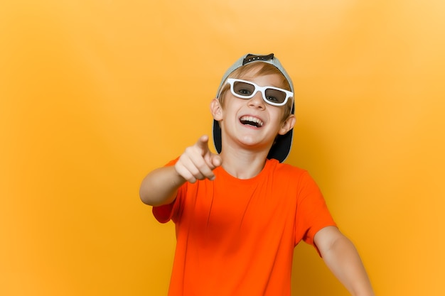 Un niño con gafas para ver películas señala con el dedo hacia adelante y se burla