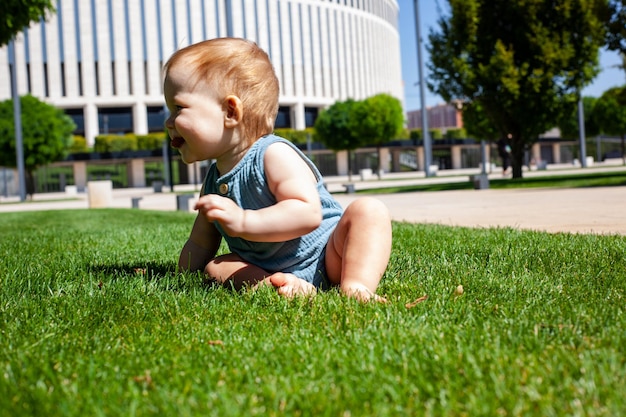 El niño gatea aprende a gatear sobre la hierba verde en el parque en verano