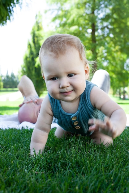 El niño gatea aprende a gatear sobre la hierba verde en el parque en verano