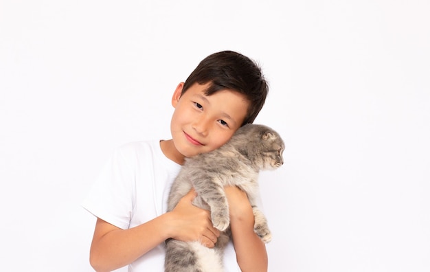 Niño con gatito gris en manos, aislado en blanco