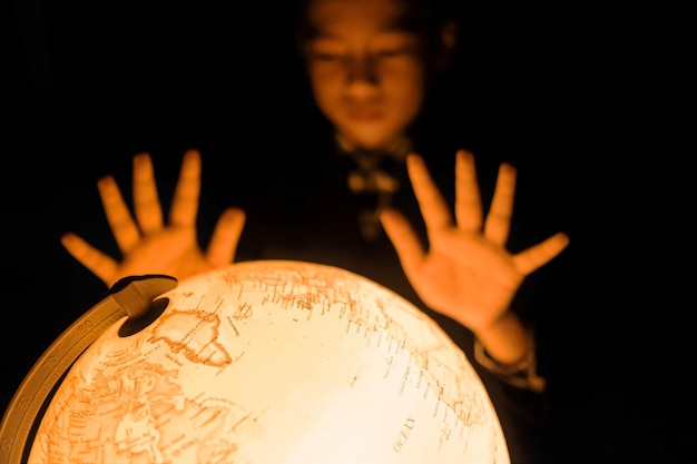 Foto niño gestando por un globo iluminado contra un fondo negro