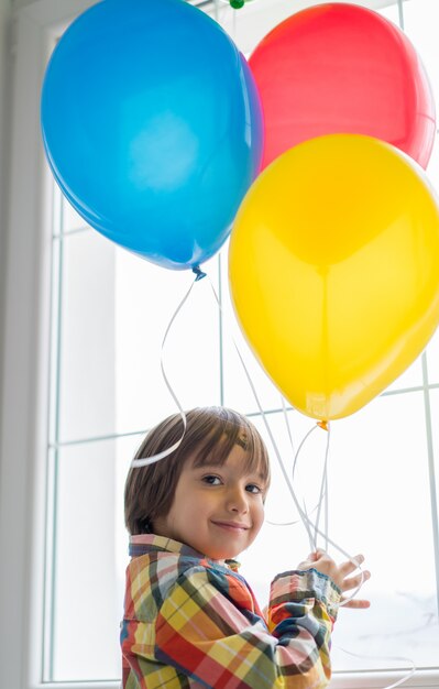 Niño con globos frente a la ventana