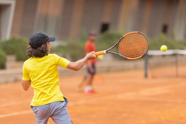 Un niño golpeando la pelota de tenis