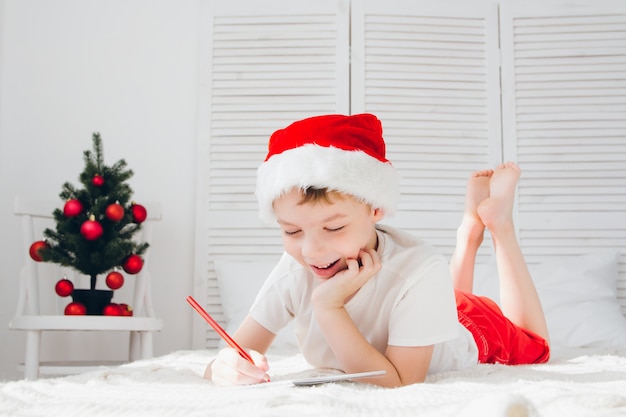 Niño con una gorra roja escribe una carta a Santa