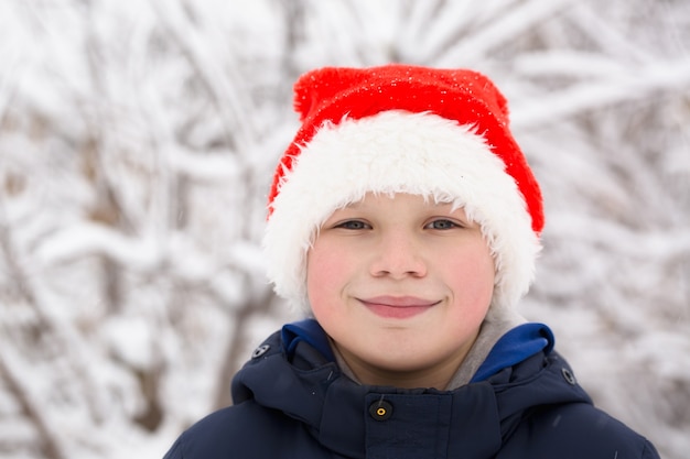 Niño de gorra roja con el telón de fondo de la naturaleza nevada