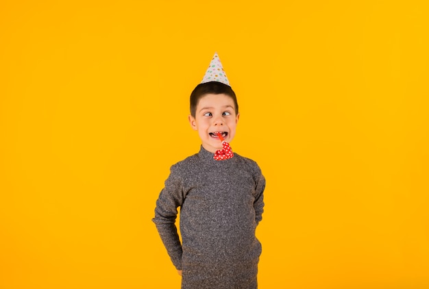 Un niño con una gorra y un silbato sobre un fondo amarillo