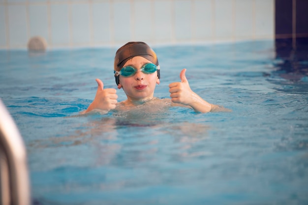 Niño con gorro de baño y gafas de natación en la piscina