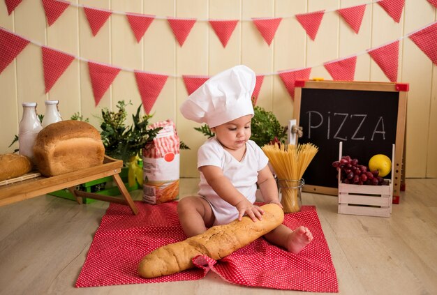 Un niño con un gorro de cocinero blanco sostiene un pan