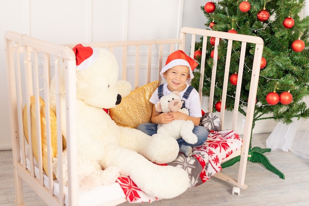 Niño con gorro de Papá Noel cerca del árbol de Navidad