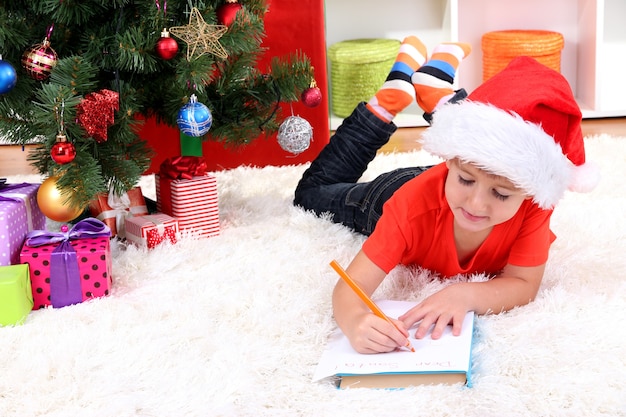 Niño con gorro de Papá Noel escribe carta a Papá Noel