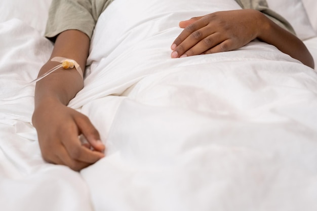 Niño con gotero en el brazo acostado en la cama