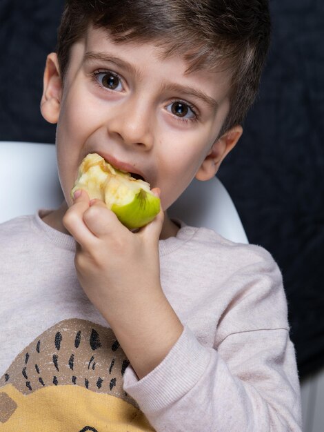 Foto niño gracioso comiendo manzana niño guapo con manzana verde alimentos saludables frutas disfruta de la comida