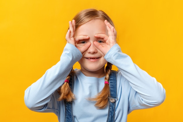 Niño gracioso se divierte y hace gafas con los dedos