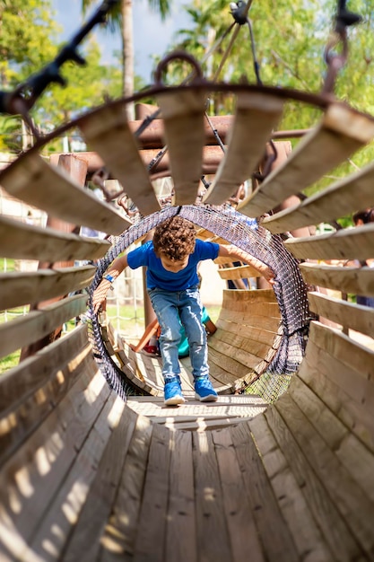 Foto niño gracioso en un patio de recreo cruzando a través del interior de un tubo de madera