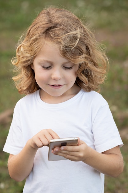 Niño gracioso con el pelo largo con un móvil