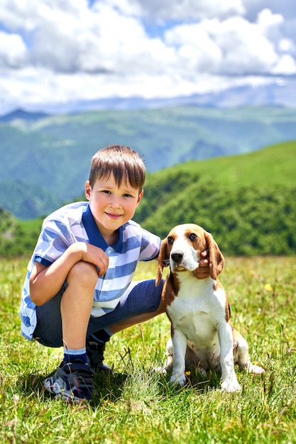 Foto niño gracioso con un perro en las montañas.