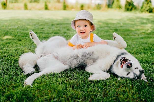 Un niño gracioso posando con el perro en el jardín.