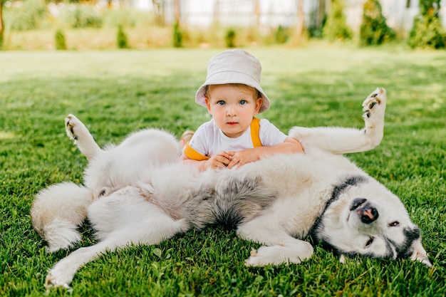 Un niño gracioso posando con el perro en el jardín.