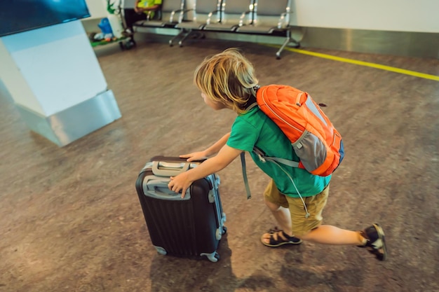 Un niño gracioso que se va de vacaciones con una maleta en el interior del aeropuerto