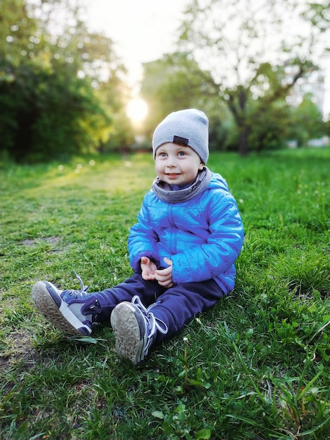 niño gracioso sentado en la hierba