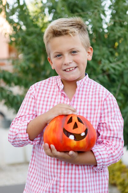 Niño gracioso sosteniendo una calabaza grande