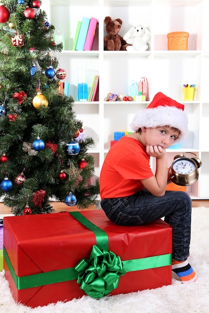 Niño con gran regalo y reloj en previsión del año nuevo