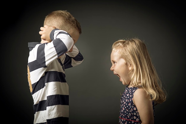 Foto niño grita y niño se tapa los oídos