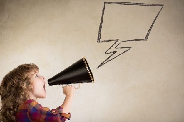 Foto niño gritando por megáfono vintage. concepto de comunicación. estilo retro