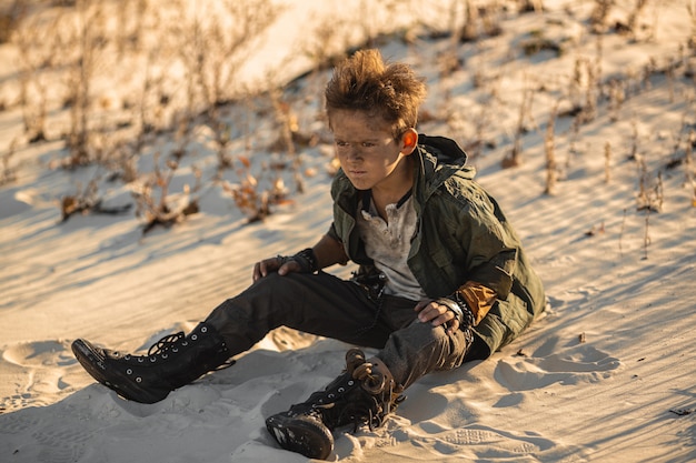 Niño guerrero post-apocalíptico al aire libre en el desierto del desierto